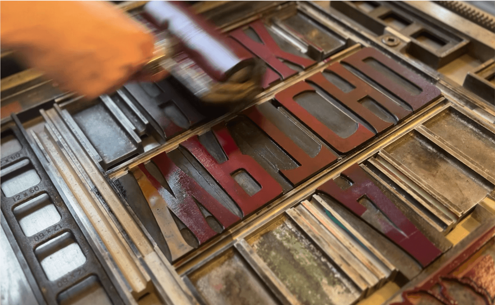 Close-up of hand rolling ink onto vintage letterpress metal type blocks