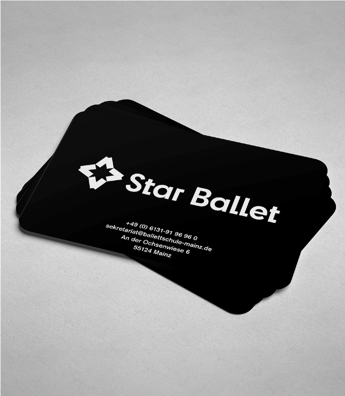 Black business cards with white Star Ballet logo stacked in a neat pile