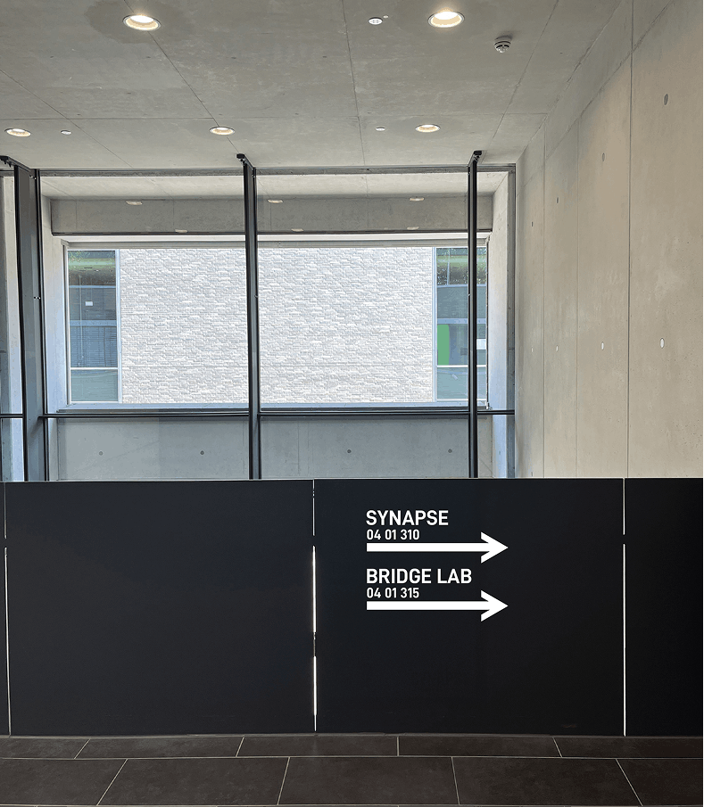 Interior wayfinding sign pointing right to Synapse and Bridge Lab