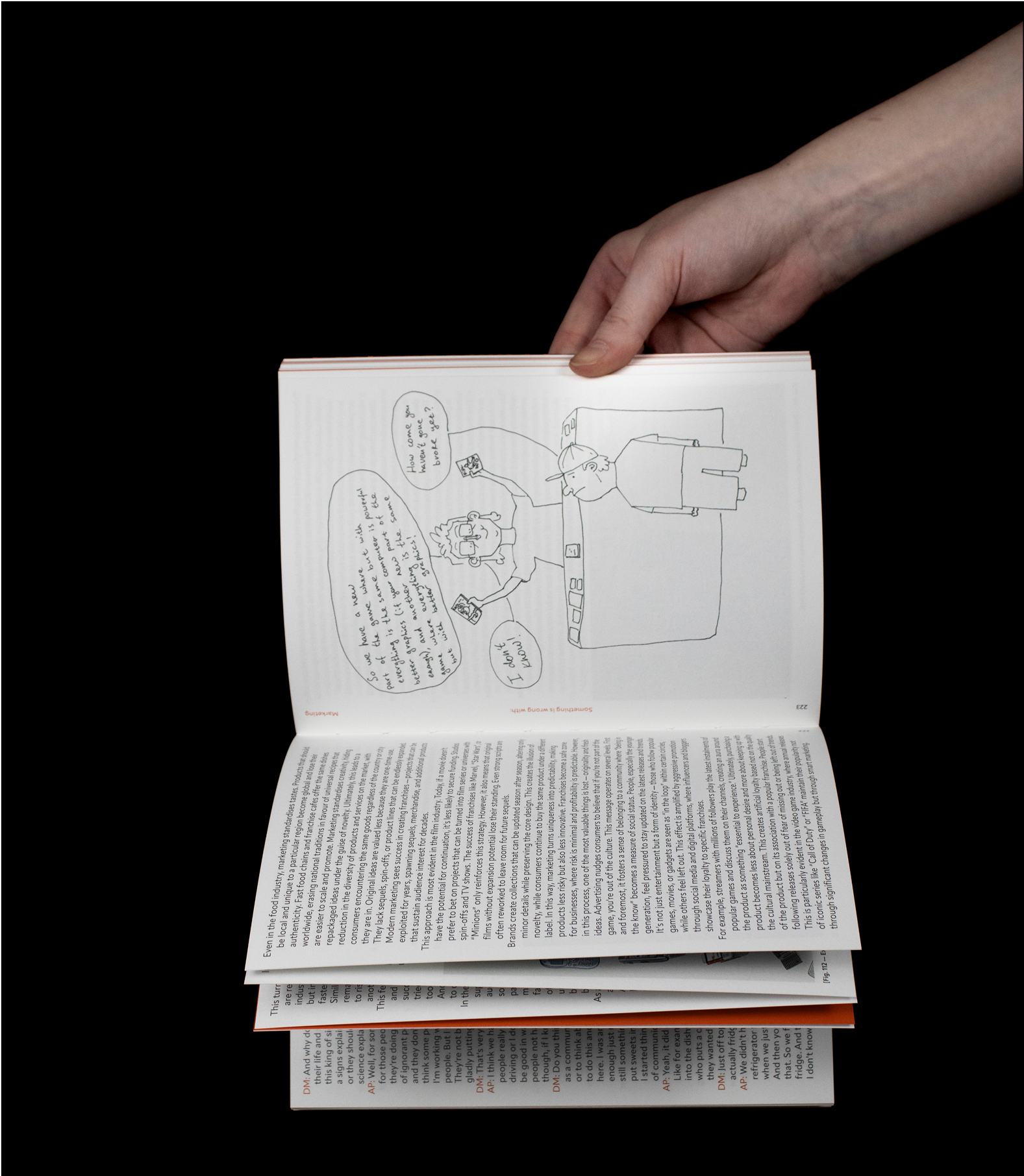 Hand holding open book showing cartoon and body text spread